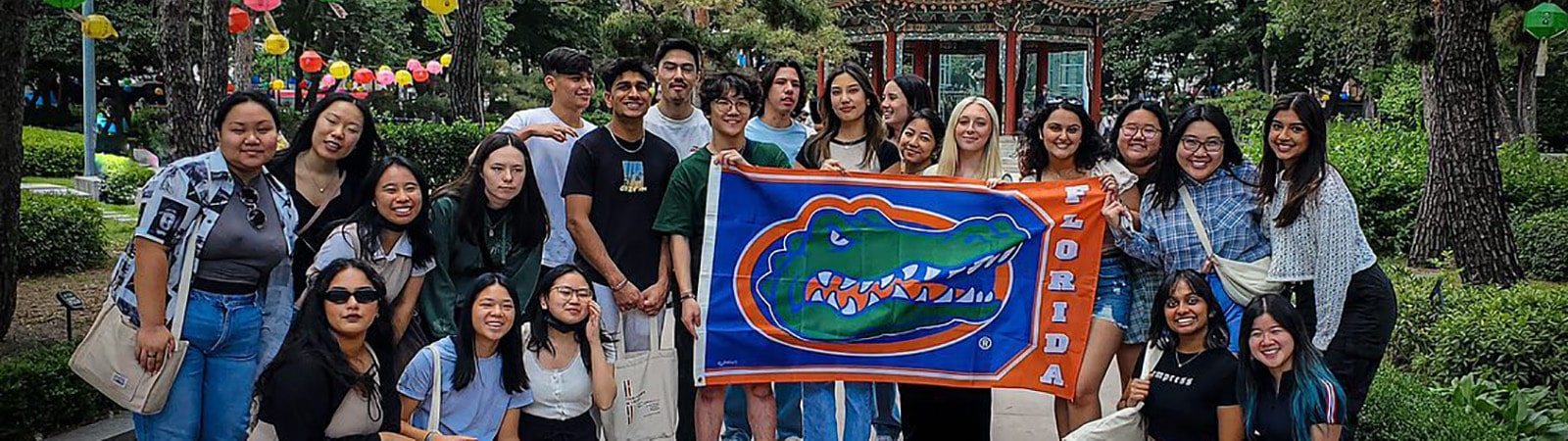 Group of students studying abroad in South Korea posing for a group photo while holding a Florida Gators flag.