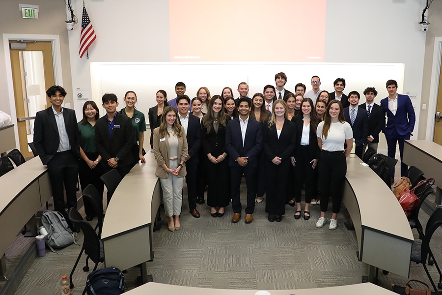 Group of students posing at the front of a Heavener Hall classroom.