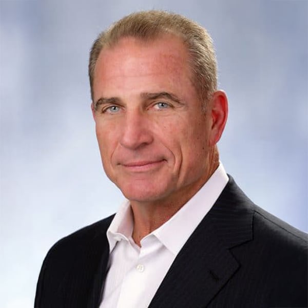 Professional headshot of Jim Heistand, a middle-aged man with short light hair, wearing a black suit jacket and white dress shirt, smiling slightly with a light blue-gray background.