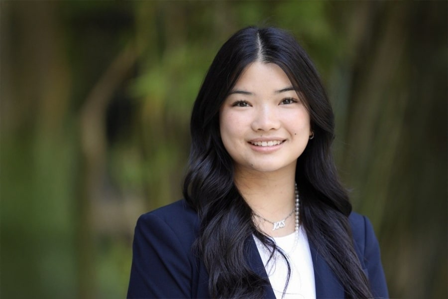 Kayla Sneiderman, Director of Rotary Operations for Business Ethics Ambassadors, smiles in an outdoor professional headshot with a blurred green background.