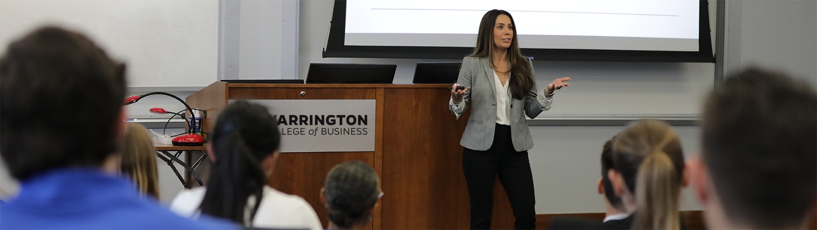 A speaker standing in front of a screen talks to a classroom of students enrolled in the University of Florida Warrington College of Business' MS in Real Estate program