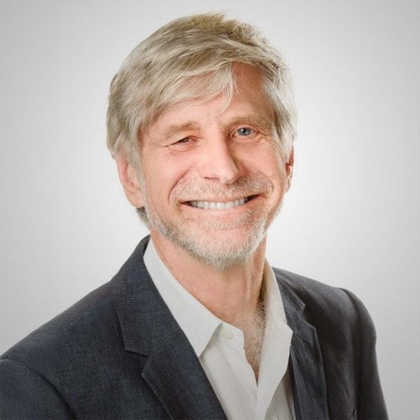 Portrait of Nathan S. Collier, a smiling older man with gray hair and beard, wearing a dark blazer over a white shirt, posed against a plain white background.