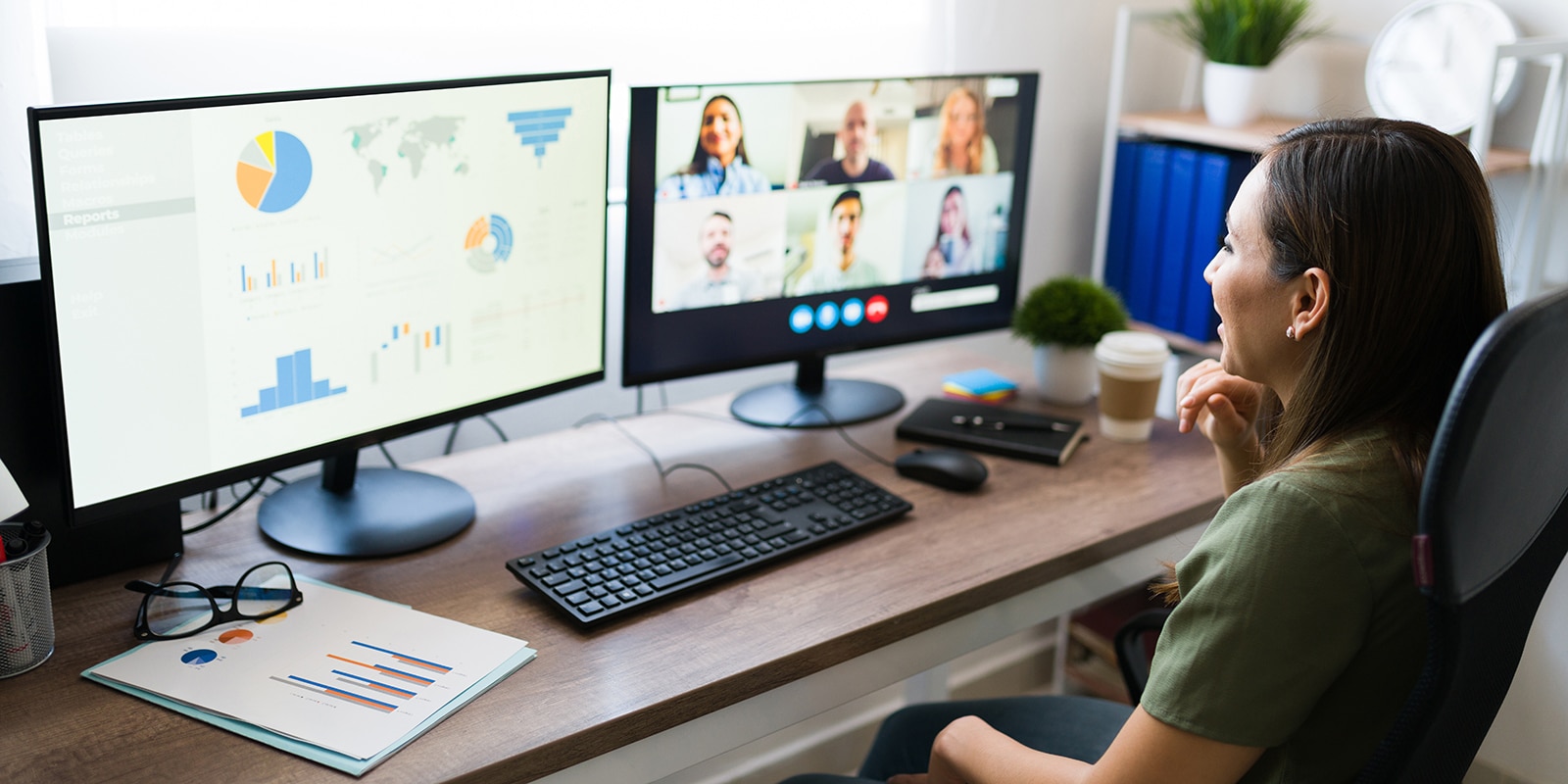A student from UF Warrington's Online MS in Business Analytics program reviews two computer monitors, one with their classmates in Zoom and another with graphs