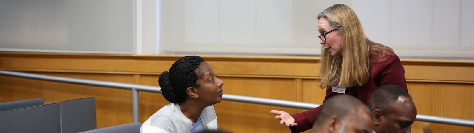 A PURC team member engages in a one-on-one conversation with a participant during a training session, offering guidance and support in a classroom setting.