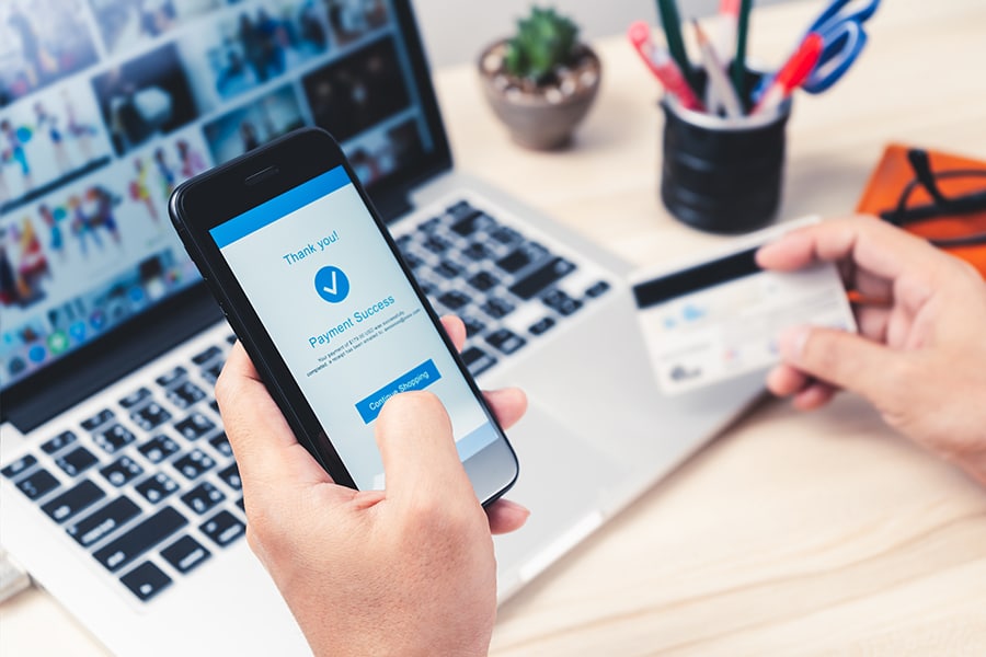 Hands using smartphone with credit card making a payment.