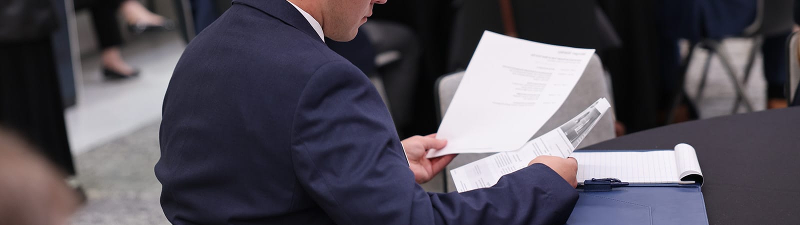 Business man sitting at a table and holding papers in his hands.