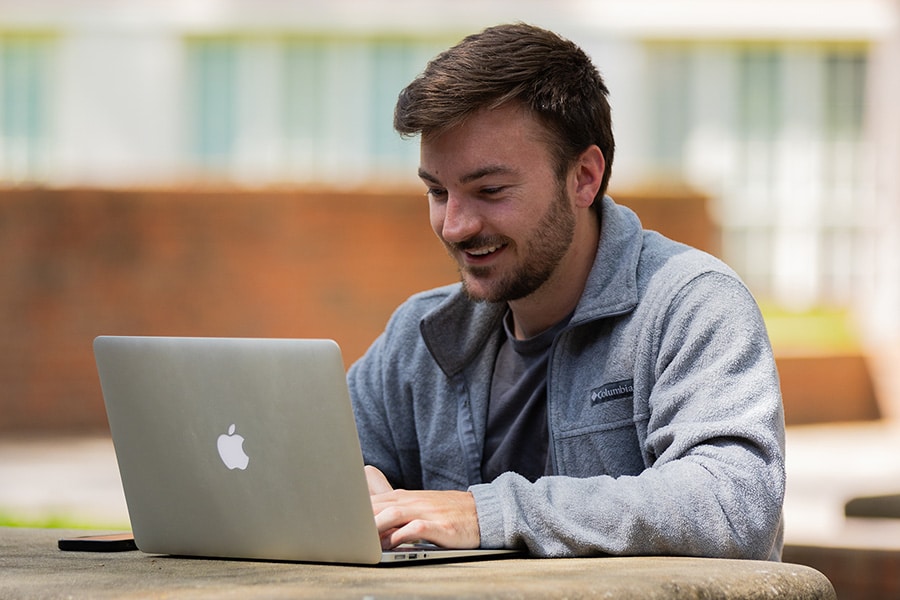 Young man sitting outside on the computer.