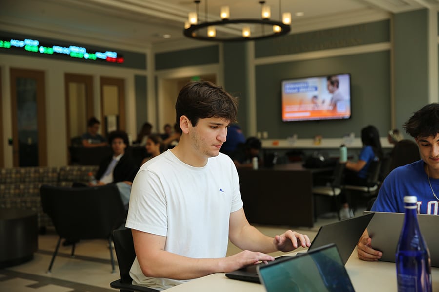 Student working at his laptop in a study hall.