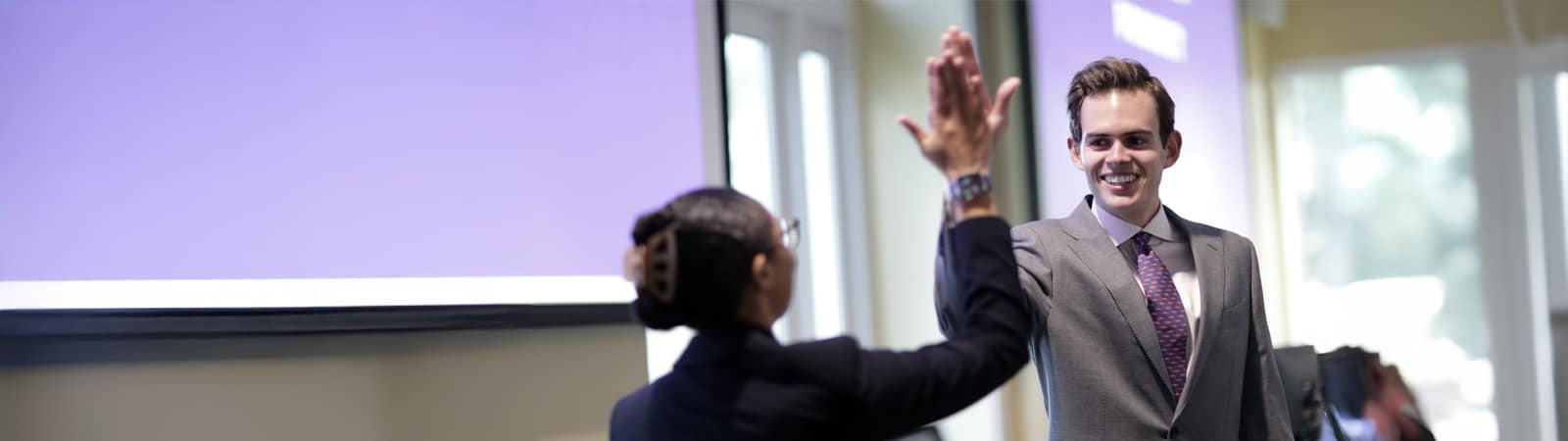 A male and female student high-five each other. 