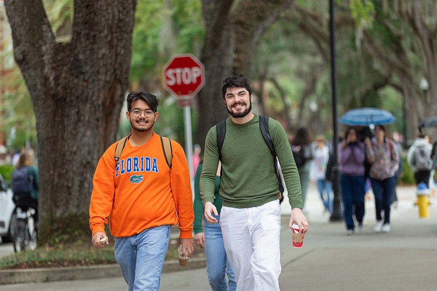 Two young men walking on campus and smiling at the camera.