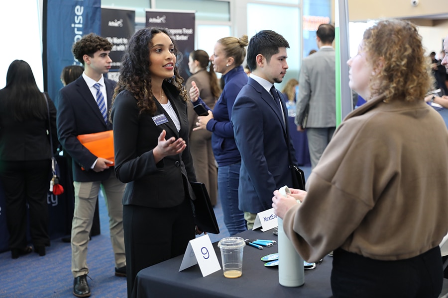 A professionally dressed female student speaking to a recruiter. 