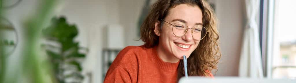A student in the University of Florida Warrington College of Business' Online BSBA program smiles at the computer screen while completing a group assignment