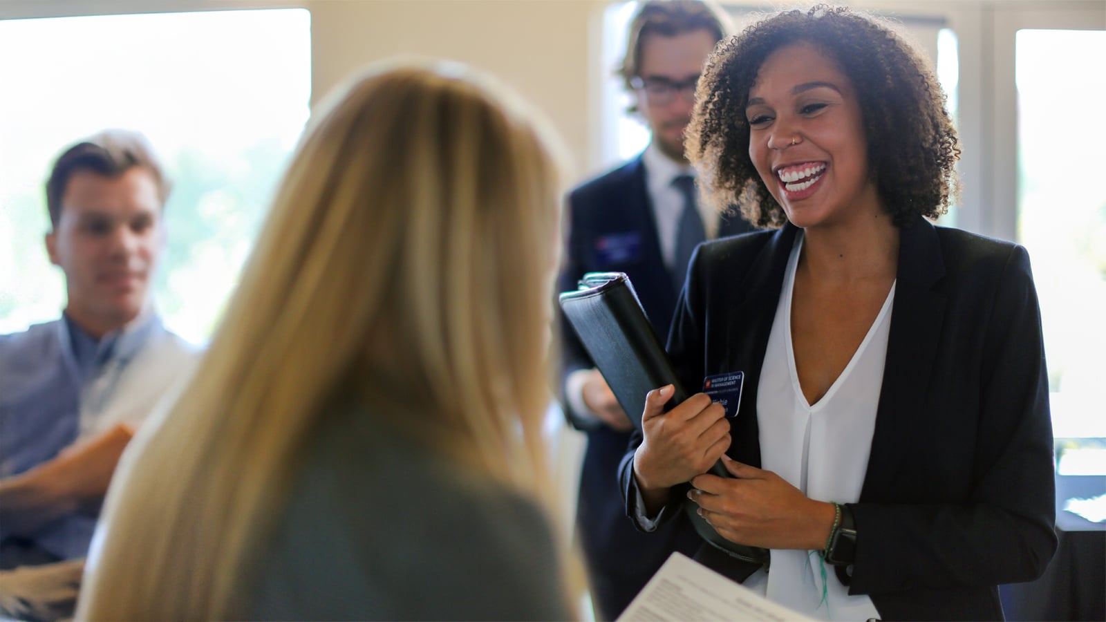 A smiling student in professional attire speaks with a recruiter at a career event.