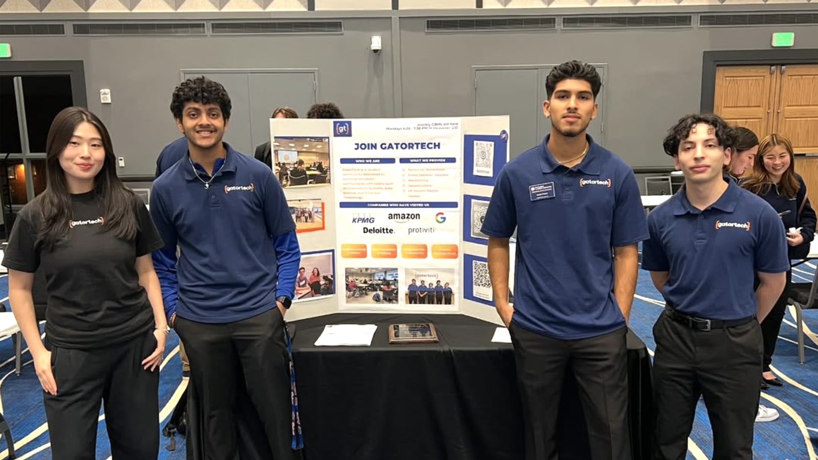 Group of GatorTech student members standing beside a recruitment display at an event