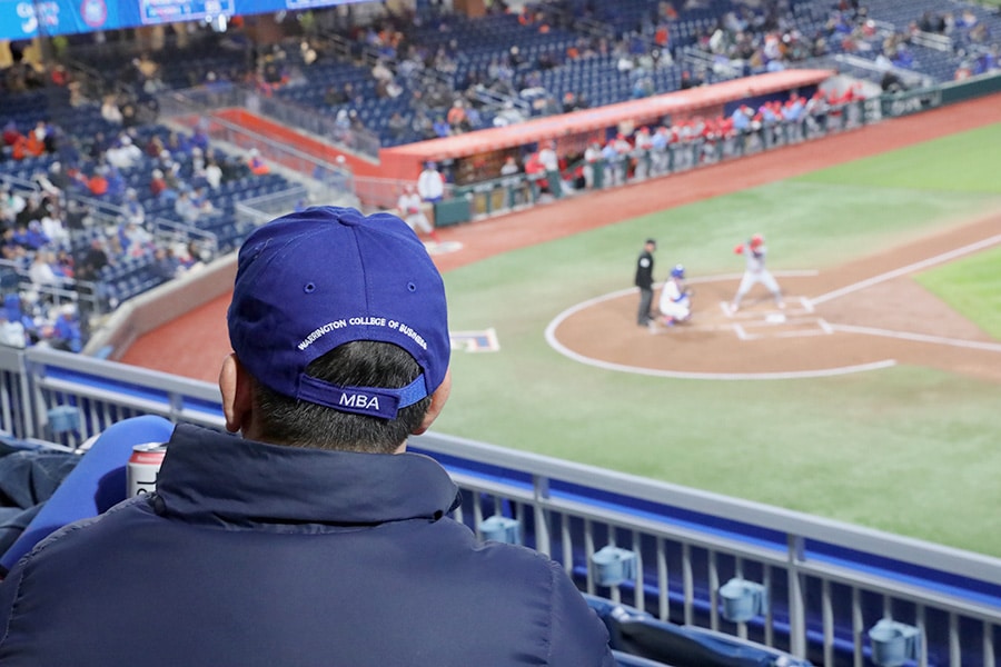 Closeup of a man's hat at a baseball game that reads "Warrington College of Business MBA".
