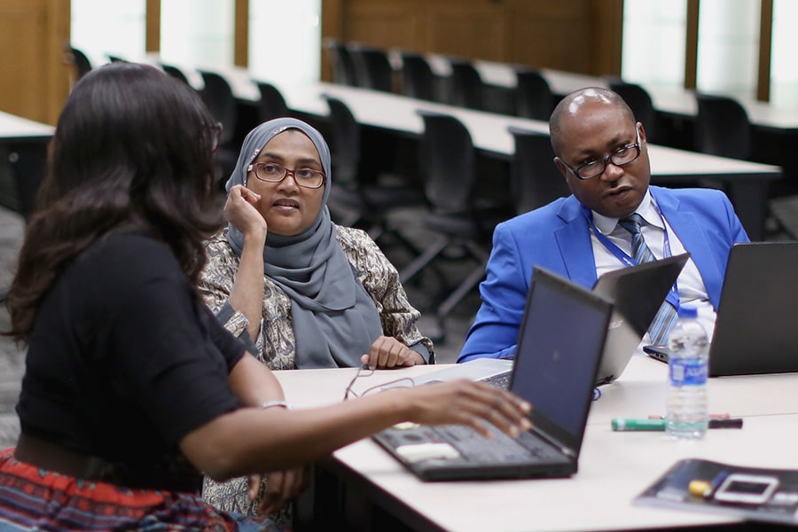 Two women and a man sitting at a table together with their laptops.