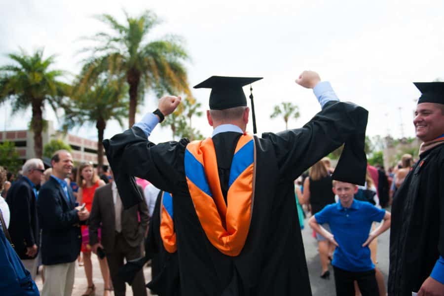 back of uf graduate with cap and gown with his hands up