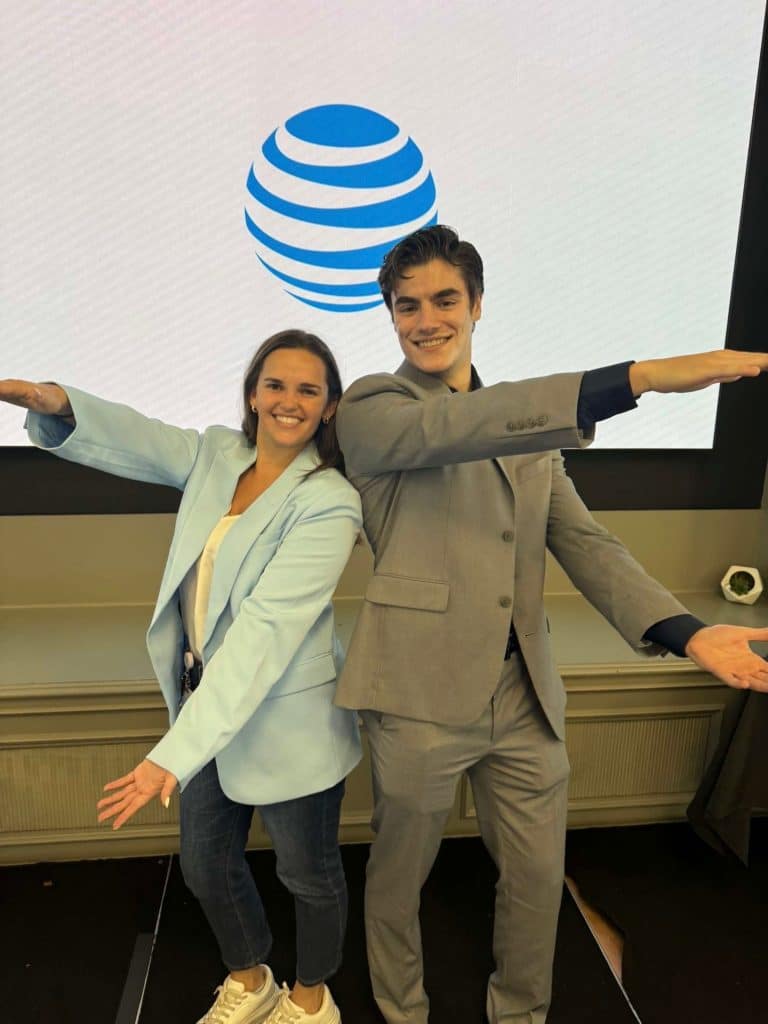 Danielle and Ethan stand in front of the AT&T logo while doing a Gator Chomp.