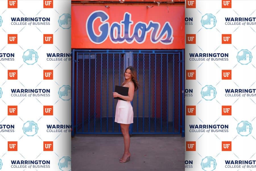 grace field standing in front of gator sign with diploma