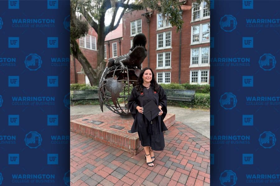 sophie zabell standing in front of gator statue with cap and gown