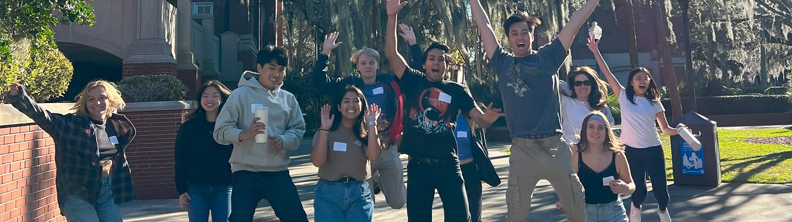 Group photo of Global Business Society students jumping in the air in front of Century Tower.