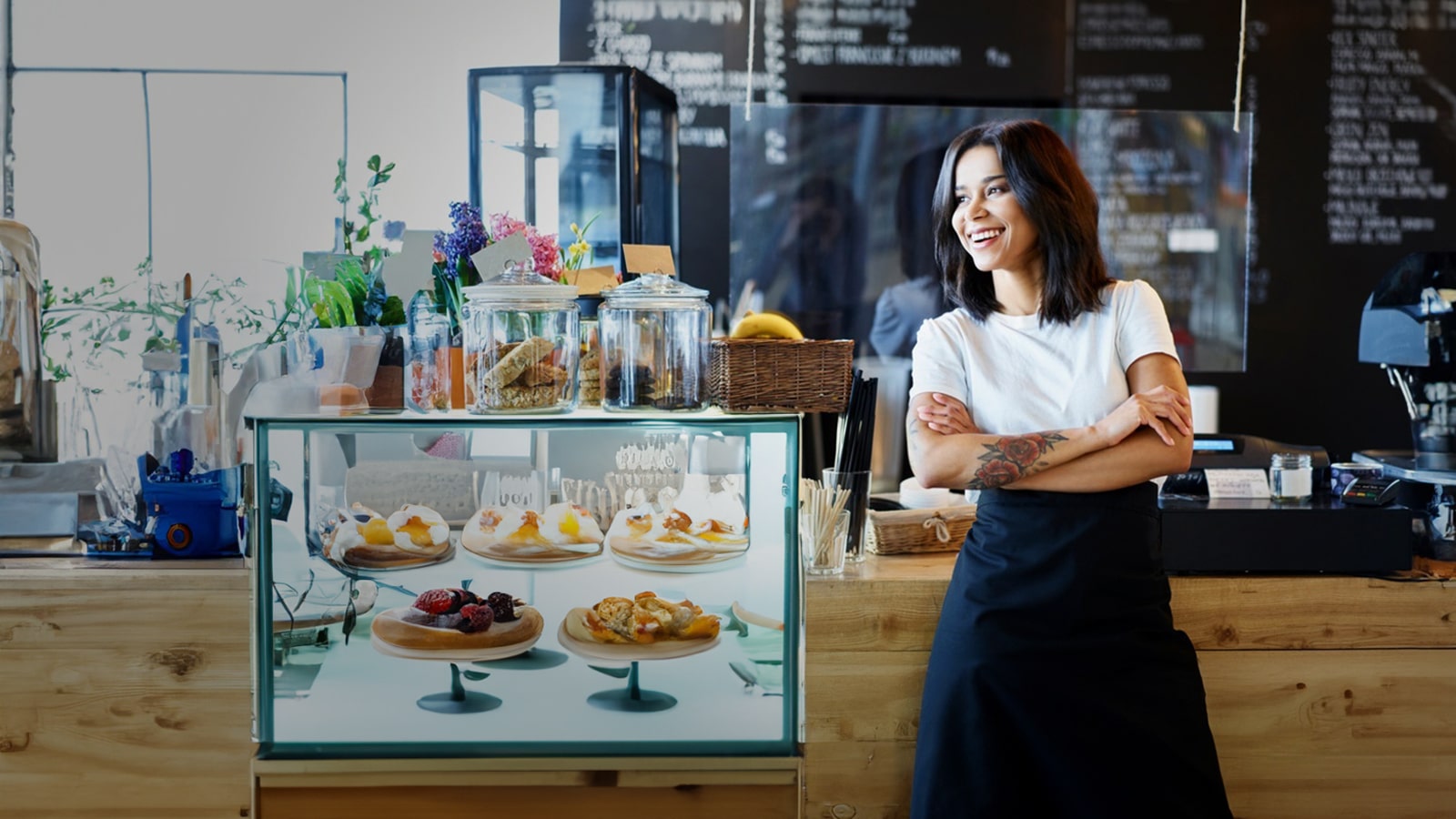 Cafe owner in front of their baking case. 