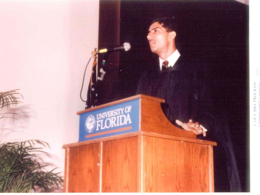 Anjan Lahiri speaking at a podium during his MBA graduation at the University of Florida. 