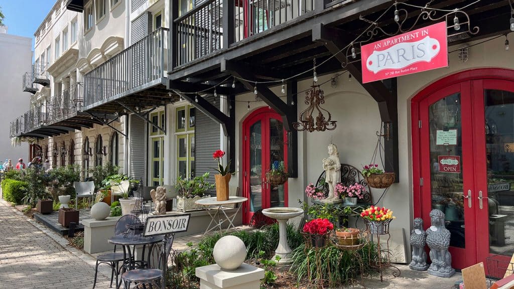 A brick walkway along shops with outdoor seating, landscaping and balconies