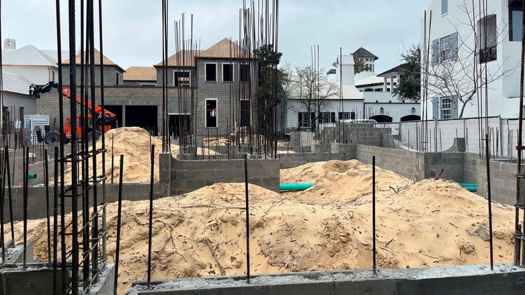 Alys Beach site showing homes in various stages of construction as a foundation with rebar fills the foreground.