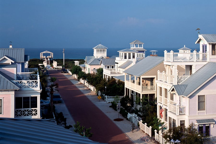 Homes in Seaside, FL lining the street with the Atlantic Ocean in the background.