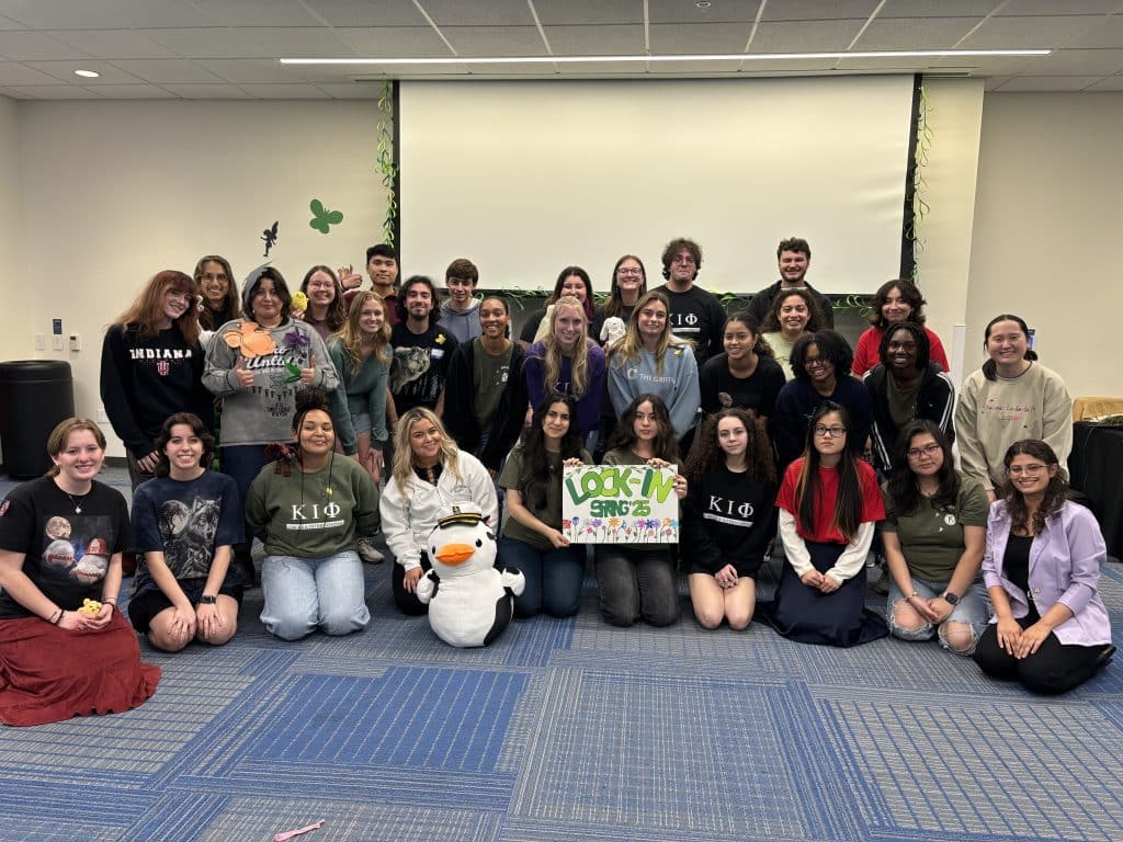 Angelina Boughanem poses with fellow CKI members for a group photo with a sign that says "Lock-In Spring '25"