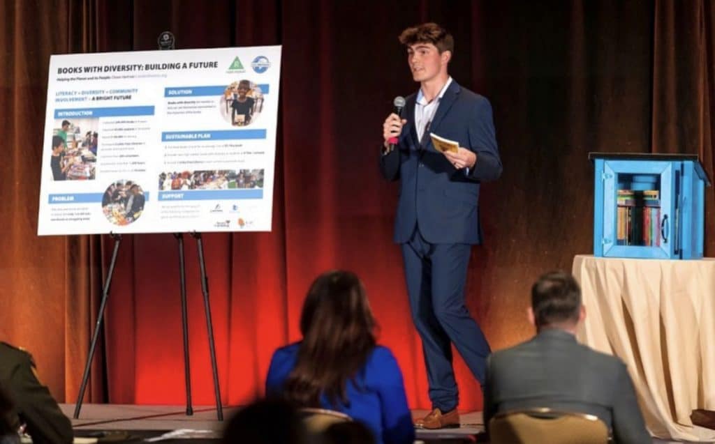 Chase Hartman presents on a stage about literacy.