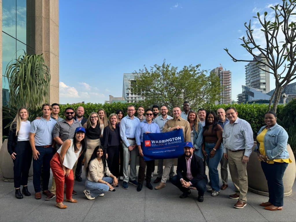 Group Photo of MBA students holding a "Warrington College of Business University of Florida" flag