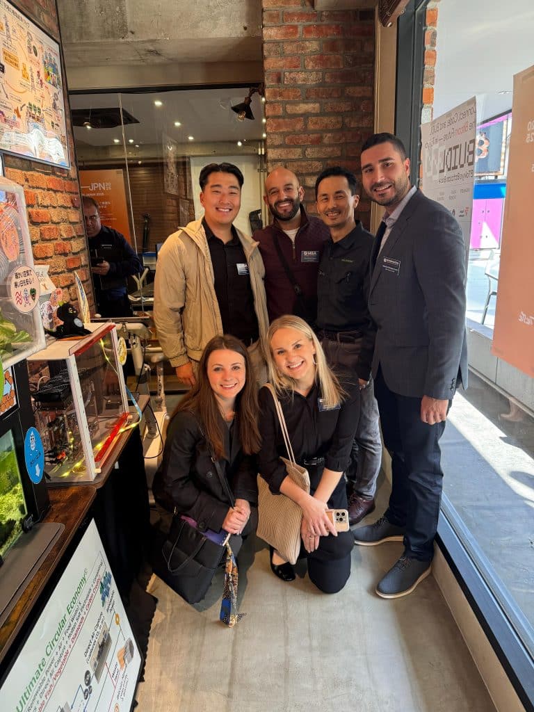 MBA team standing and squatting in a group smiling in a small cafe