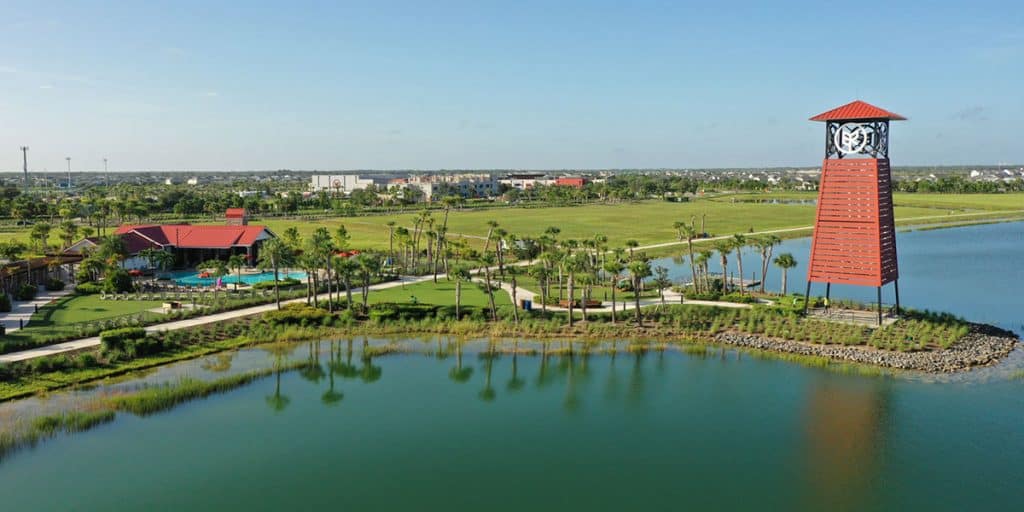 A view of Babcock Ranch clubhouse and pool with a path winding out to an artistic structure situated on a piece of land that juts out into the water