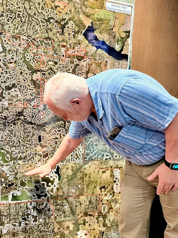 Rex Jenson leans over to indicate an area on a map which is hanging on a wall