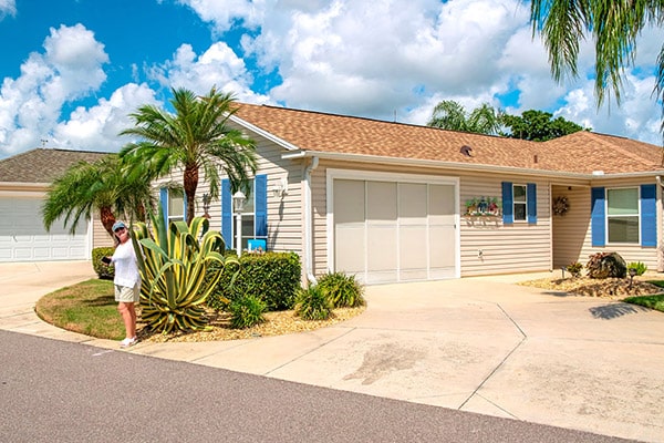 A woman stands next to the landscaping by a home in The Villages