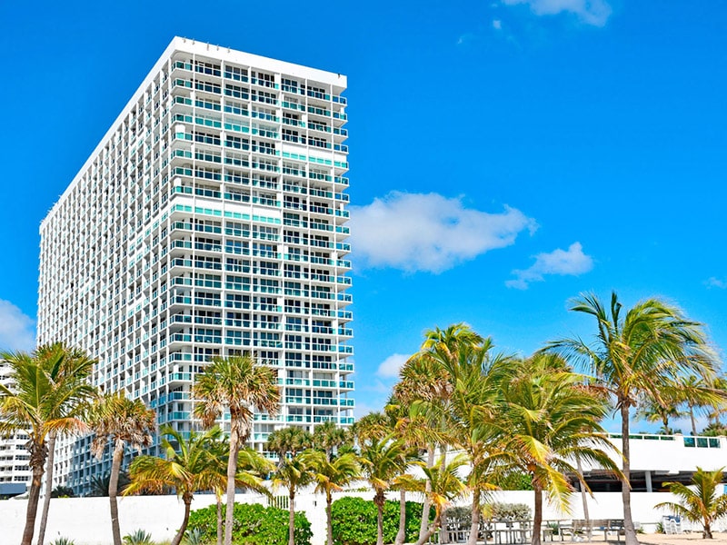 Tall condo with palm trees in the foreground