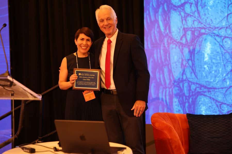 Lisa Dilts holds a plaque with her alumna of the year award while standing next to David Ling.
