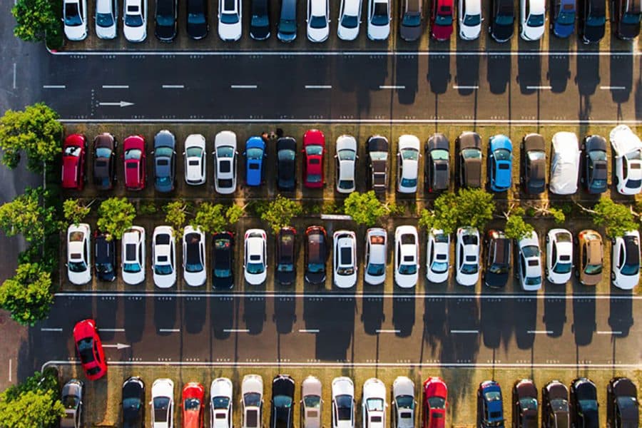 An aerial view of a parking lot with many cars and only one empty parking spot